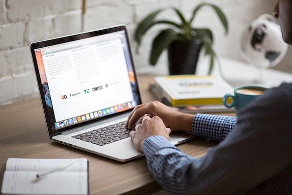 man in checked shirt typing on laptop